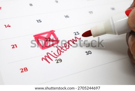 Hand Using a Red Marker to Circle an Important Midterm Exam Date on a Calendar, Signifying Academic Deadlines and Planning