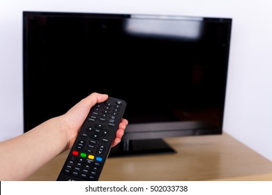 Hand Using A Remote Control To Turn Off On On The TV With An Empty Screen