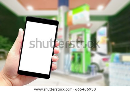 hand using smartphone with blank screen on abstract blurred background of gas station at night