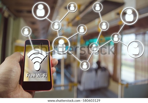 Hand using Smartphone and is using free wifi with\
icon social media connection concept, Wifi Free on Bus concept on\
blurred background of people in public transportation bus, color\
tone effect.