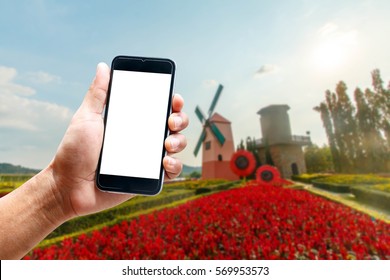Hand using smartphone mobile in the vertical position, background blur flower garden.