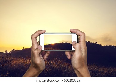 Hand Using Smartphone Taking Photo Of Tropical Mountain Landscape In Sunset