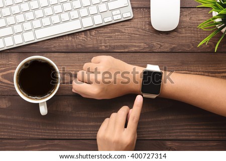 hand using smartwatch on desk top view