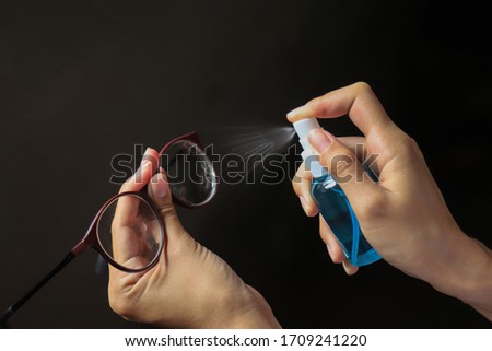 hand using spray to clean glasses in home from using in working daily lfie activity. clean tools in life for protect from bacteria and virus concept 