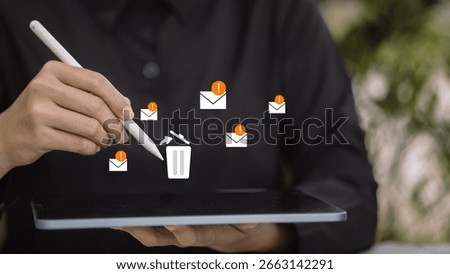 Hand using stylus to delete spam warning emails on tablet, concept of digital clutter management, email security and inbox cleanup.