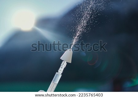 Hand using a syringe with a mucosal atomization decive (MAD) for intranasal application of drugs.