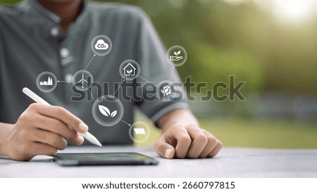Hand using tablet with floating green energy, renewable, and sustainability icons, eco-friendly technology, climate change, and environmental innovation concept.