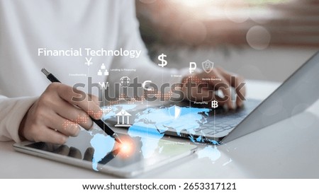 Hand using tablet and laptop with global financial technology interface, showing fintech services like e-wallet, cryptocurrency, mobile banking, and online payment systems.