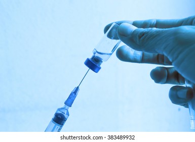 hand with vaccine bottle on blue filter