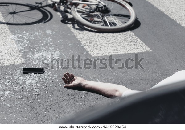 Hand of victim on pedestrian crossing\
next to bike after dangerous traffic\
accident
