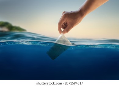 Hand Of Volunteer Cleaning A Plastic Up Floating In Ocean. Plastic Pollution In Ocean And Sea Concept.