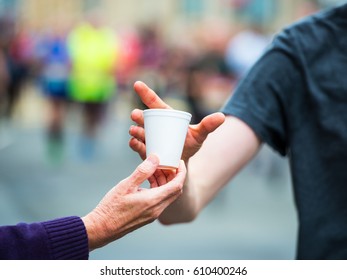 Hand Of A Volunteer Giving A Cup Of Water At A Refreshment Point In A Marathon Race To Runners.