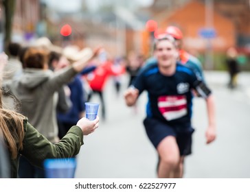 Hand Of A Volunteer Giving A Cup Of Water At A Refreshment Point In A Marathon Race To Runners.