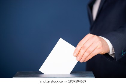 Hand of a voter putting vote in the ballot box. Election concept.