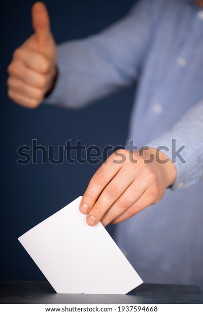 Hand of a voter putting vote in the ballot box.\
Election concept.