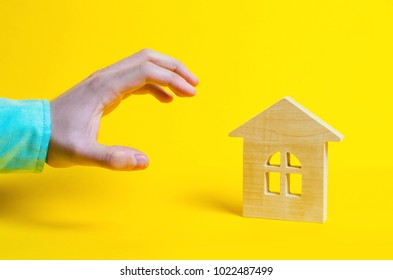 A Hand Wants To Take The Home. A High Demand For Real Estate Or Seizure Of Property Concept On A Yellow Background