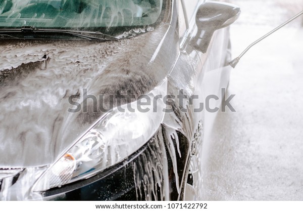Hand\
washing black car with soap and water\
pressure