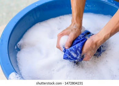 Hand Washing Clothes In Blue Basin