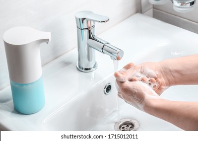Hand washing with soapy water in the bathroom. A young guy washes his hands with soap. The fight against coronavirus.