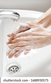 Hand Washing In White Sink. Water Flows From A Faucet At Soapy Female Hands. Covid-19 Coronavirus Protective Measure.