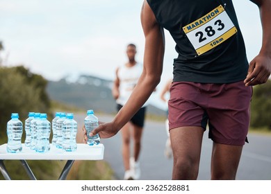 Hand, water and a marathon runner in a race or competition closeup for fitness or cardio on a street. Sports, exercise or running with an athlete grabbing a drink while outdoor on a road for training - Powered by Shutterstock