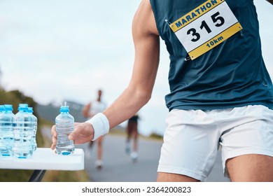 Hand, water and running a marathon race for competition closeup with fitness or cardio on a street. Sports, exercise or health and a runner or athlete person with a drink while on a road for training - Powered by Shutterstock