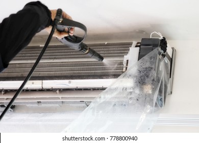 Hand And Water Spray Are Cleaning The Air Conditioner.Focus At Air Conditioner.