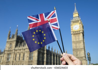 Hand Waving European Union And British Union Jack Flag In Front Of Big Ben And The Houses Of Parliament At Westminster Palace, London As The Brexit Process Moves Ahead