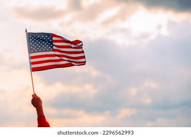 
Hand Waving the Flag of the United Stated of America. Optimistic person holding American flag celebrating citizenship
