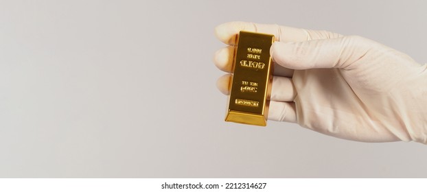 Hand Wear Latex Glove And Hold Gold Bar On White Background. 