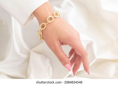 Hand Wearing A Big Gold Chain Bracelet And A White Jacket