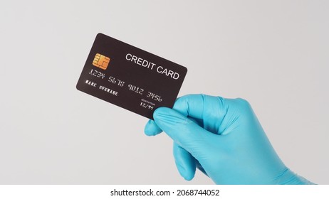 Hand Wearing Medical Glove And Holding Black Credit Card Isolated On White Background. Asian Man Hand.	