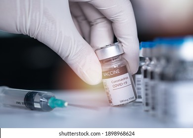 Hand wearing a medical nitrile surgical glove and pick or hold a bottle of covid19 vaccine. Vaccination, immunization, treatment to cure Covid 19 Corona Virus infection Concept