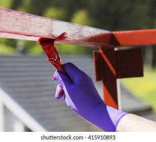 Hand wearing purple gloves and painting with a paint brush. - Powered by Shutterstock