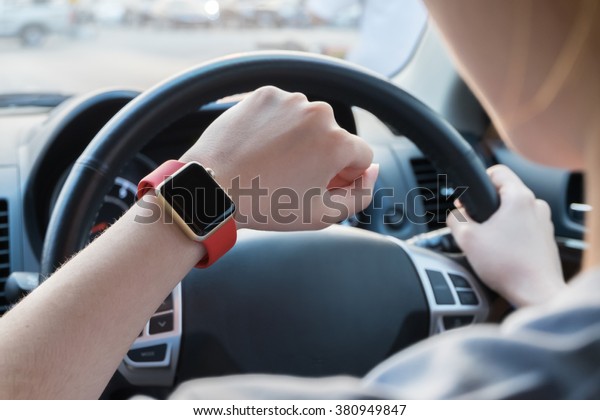 Hand wearing smart\
watch while driving car