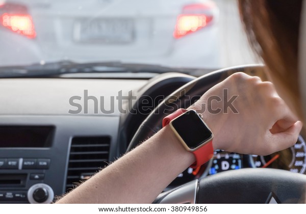 Hand wearing smart\
watch while driving car