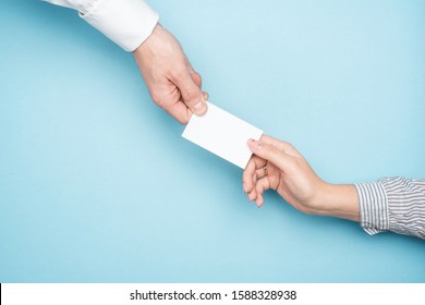 Hand In A White Shirt Holding A Blank Business Card Mockup On A Blue Background.