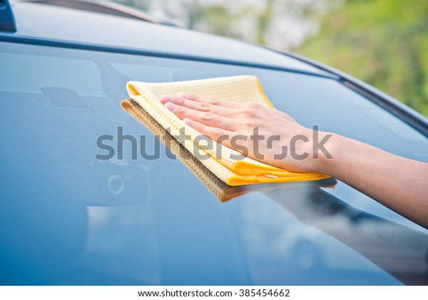  Hand wipe cleaning the car glass front with yellow\
microfiber cloth