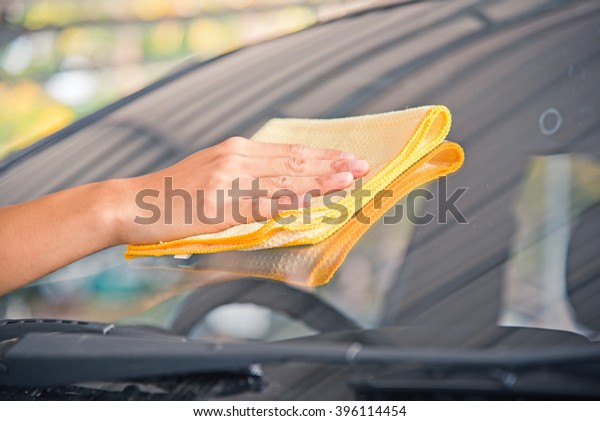 Hand wipe cleaning the car glass front with\
yellow microfiber cloth\
