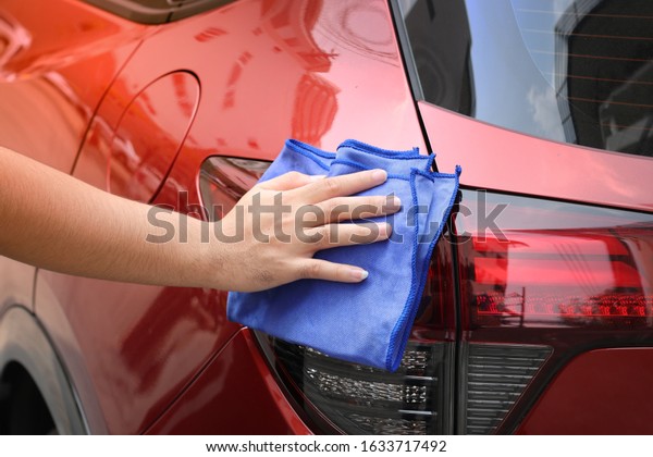 Hand\
wipe red car tail light surface with blue microfiber cloth. clean\
the car, car maintenance, car towel, wipe the\
dust