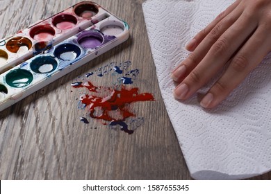 A Hand Wipes The Stain From The Paints With A Paper Towel, A Napkin.The Woman Does The Cleaning. Clean, House, Housekeeper, Cleanup And Housework.