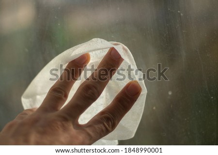 The hand wipes the window. Washing windows from marks on glass. Wet cloth in hand for cleaning the house.