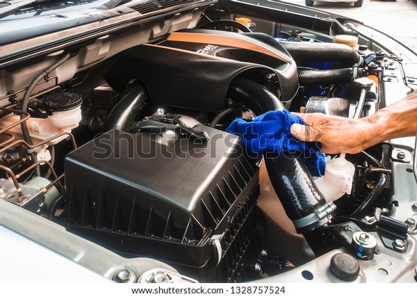 hand are wiping the car engine with blue microfiber\
cloth. maintain of car.