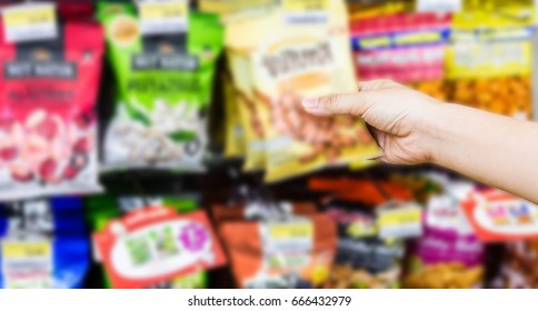 Hand Of Woman Choosing Or Taking Sweet Products, Snacks On Shelves In Convenience Store
