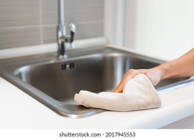 Hand of woman cleaning the kitchen counter and sink at home. Housewife doing housework concept. Closeup