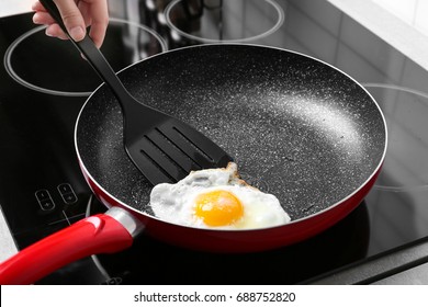 Hand Of Woman Cooking Over Hard Fried Egg Using Spatula