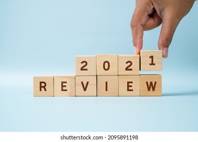 Hand of woman drop wooden blocks and change the 2021 Review over blue background
