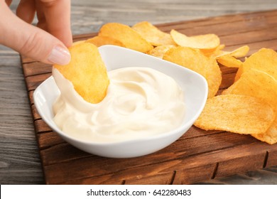 Hand Of Woman Eating Chips With Tasty Mayonnaise Sauce, Closeup