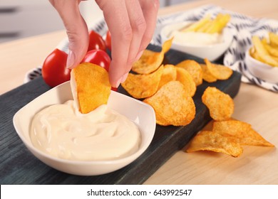 Hand Of Woman Eating Chips With Tasty Mayonnaise Sauce, Closeup