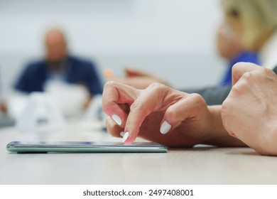 Hand of a woman or girl using a smartphone during a business meeting, conference, lesson or negotiations. Photo. Selective focus. Close-up - Powered by Shutterstock